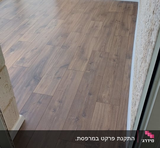 רצפת פרקט עץ בחדר עם קירות אבן